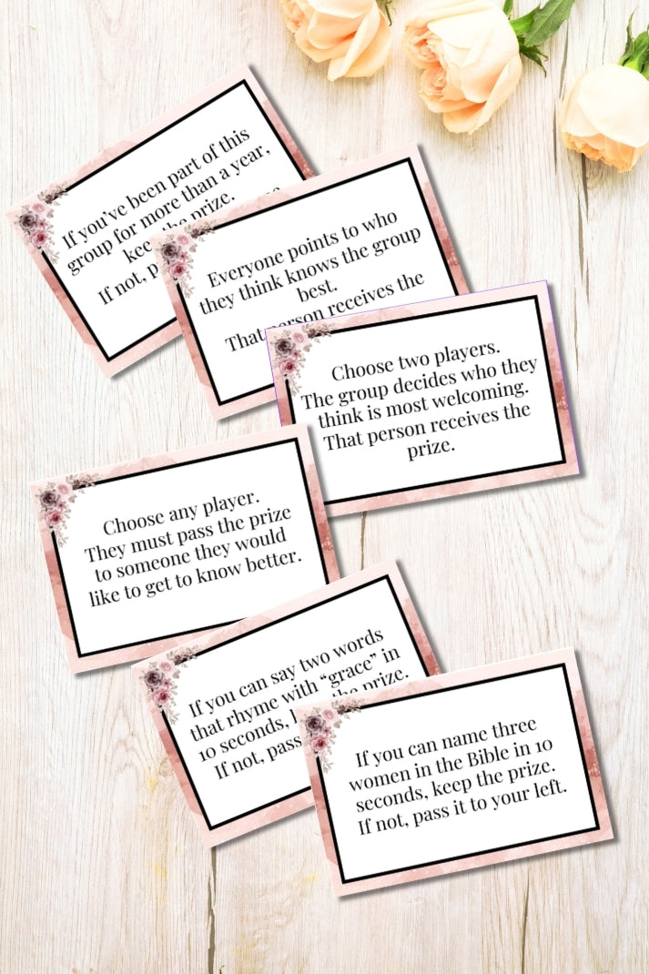 Set of cards with game instructions on a wooden surface with flowers.